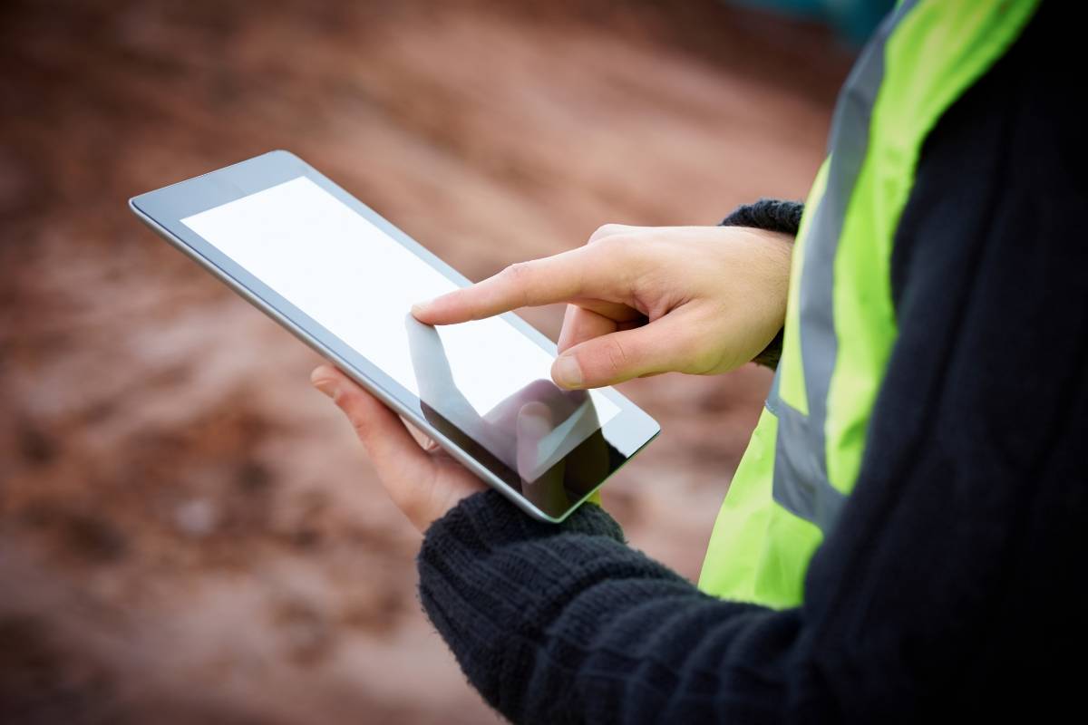 Construction worker holding a tablet and working on it
