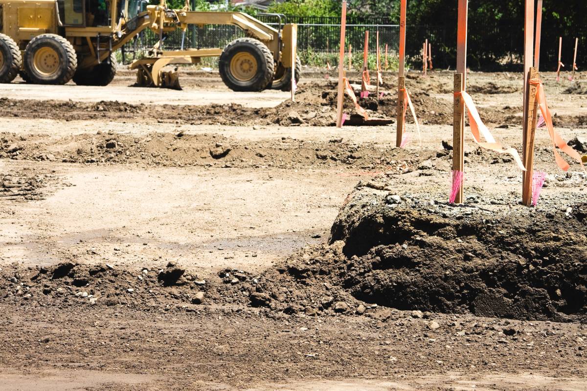 Construction site with heavy machinery and survey stakes for soil testing