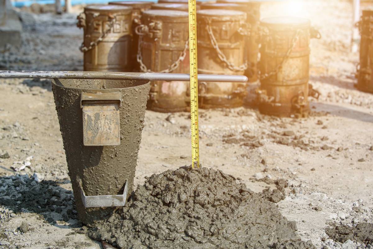 Concrete field testing slump test with measuring tape on an active construction job site